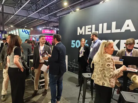 Stand de Melilla en el Mobile World Congress 2026, con visitantes conversando ante un panel que anuncia la fiscalidad reducida del territorio.